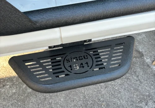 Black vehicle step bar and textured foothold below an open door